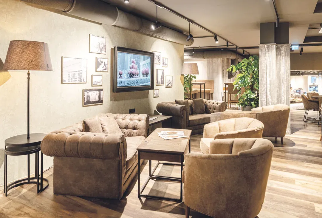 Das Wohnzimmer im Bäckerei-Café Waiblingen mit Samtsofas, Sesseln, Stehlampe und gerahmten Fotos an der Wand