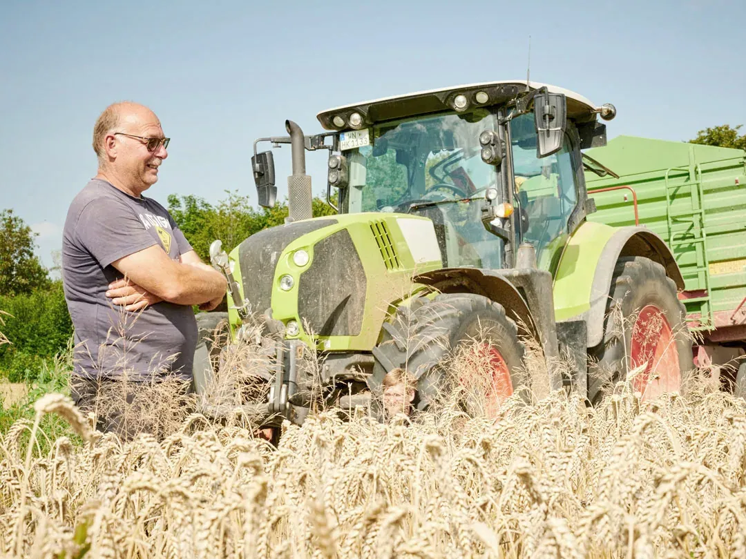 Harald Kauffmann vor dem Traktor im Weizenfeld