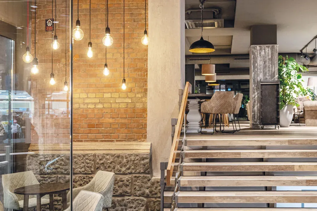 Ziegelwand mit frei hängenden Glühbirnen im Bäckerei-Café Waiblingen, davor eine Treppe mit Holzstufen
