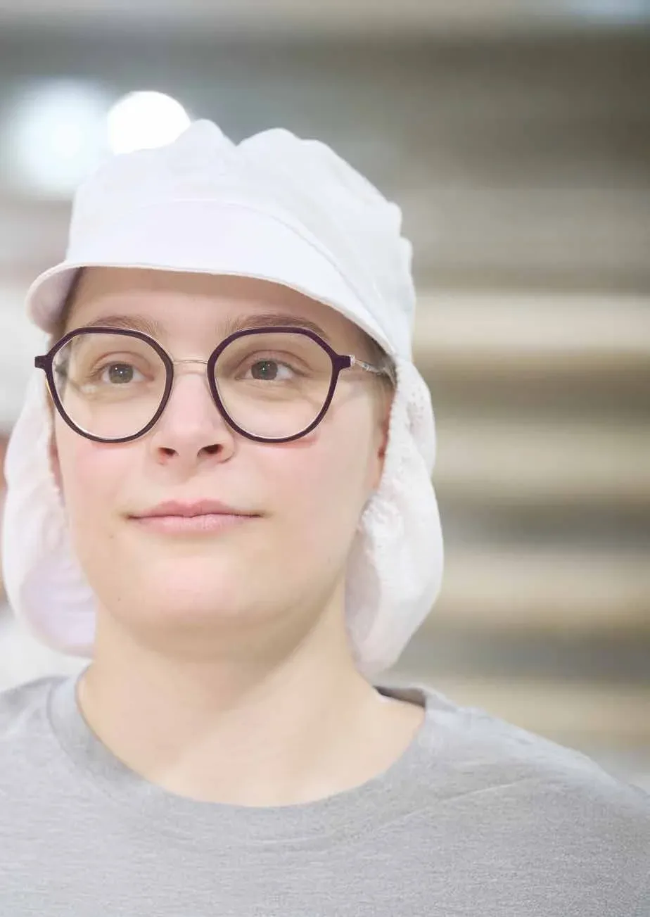 Franziska in Arbeitskleidung und weißer Haube in der Konditorei