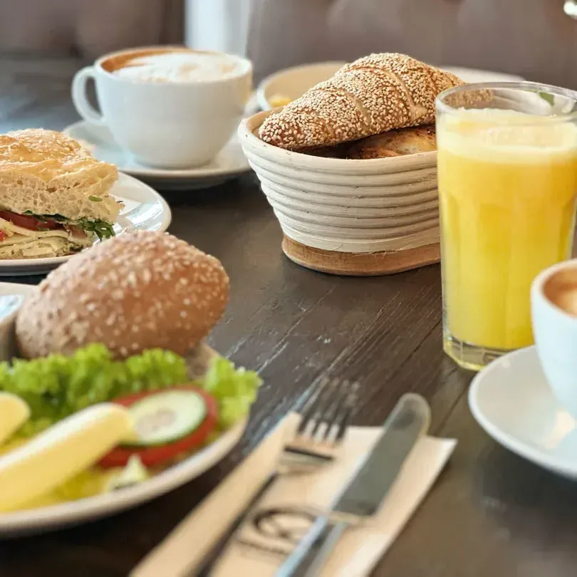 Gedeckter Frühstückstisch mit Kaffee, Orangensaft, Brotkorb und belegten Weckle im Bäckerei-Café Schwaikheim