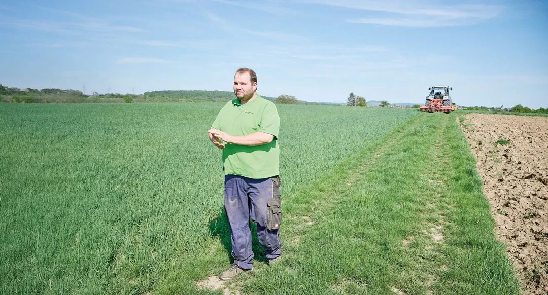 Sven Gloning auf dem Feldweg, im Hintergrund ein Traktor bei der Arbeit