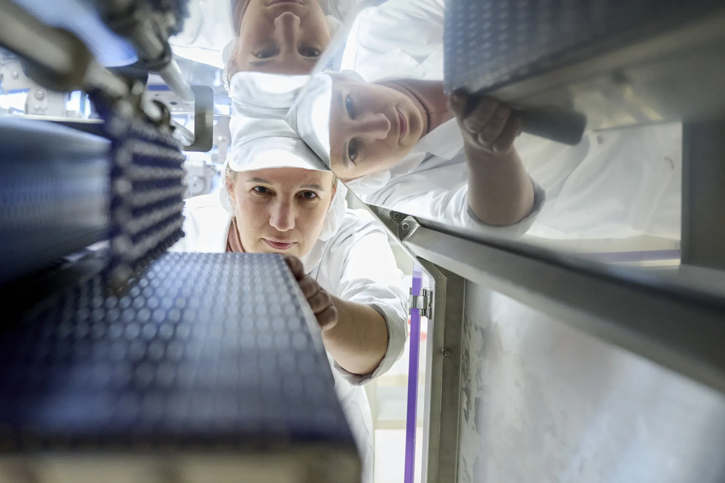 Mitarbeiterin der Qualitätssicherung greift über das Förderband der Teiglinie