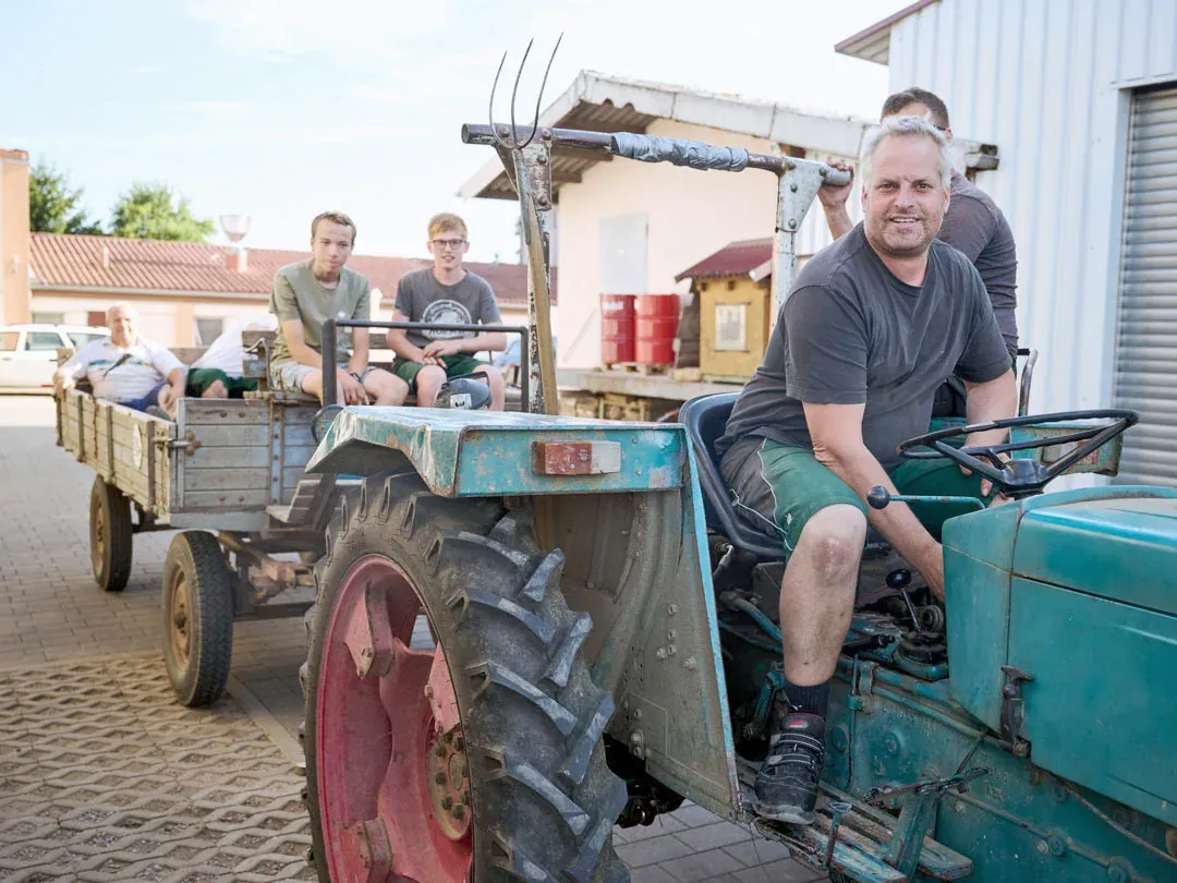 Wolfgang Bürkle auf seinem Traktor vor dem Hof, im Anhänger die Familie